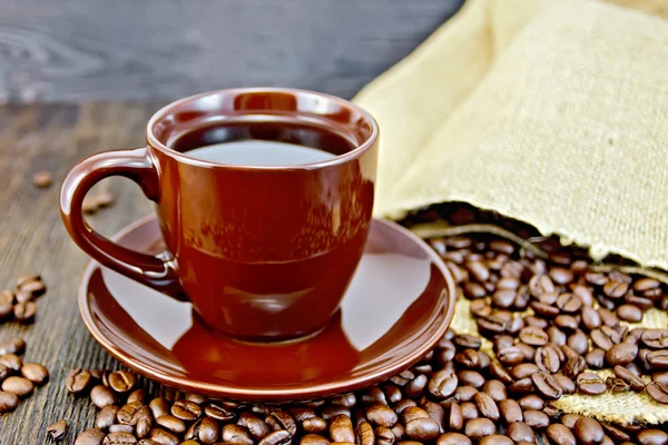 Coffee in brown cup with grains and bag on board — Stock Photo, Image