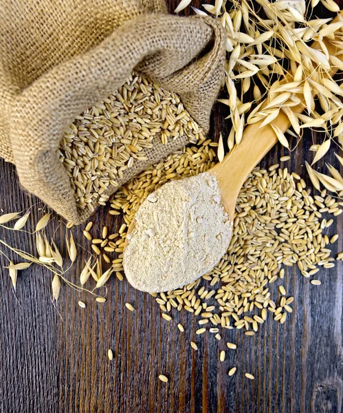 Flour oat in wooden spoon with bag on board top — Stock Photo, Image