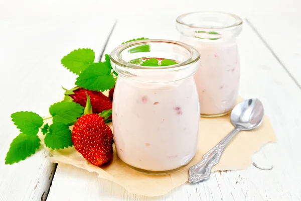 Yogurt with strawberries in jar on parchment and board — Stock Fotó