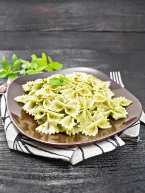 Pesto soslu Farfalle makarna, ahşap arka planda peçetede fesleğen.