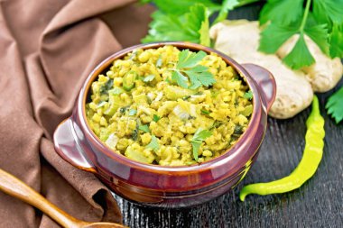 Hindistan milli yemeği bezelye, pirinç, kereviz, ıspanak, sıcak biber ve baharattan yapılmış havluyla bir kase, tahta arka planda zencefil ve kaşık.