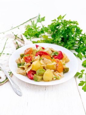 Kabaklı sebze yahnisi, lahana, patates, domates ve kremalı soslu dolmalık biber tabakta, peçetede, maydanozda ve tahta zeminde çatal.