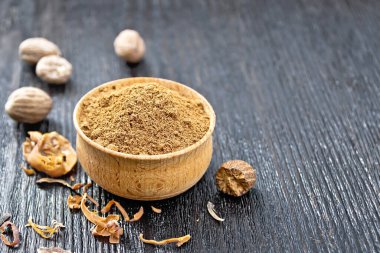 Kâsede hindistan cevizi, kurutulmuş hindistan cevizi arillus ve tahta bir arka planda fındıklar.