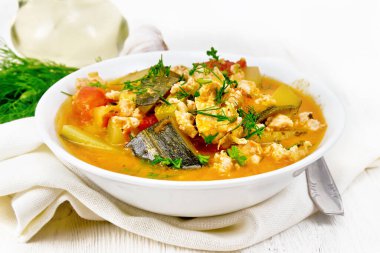 Kabak yahnisi, doğranmış tavuk ve domatesler, hafif ahşap bir arka planda peçetenin üzerinde bir tabakta otlar.