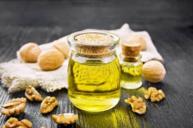 Kavanozda ceviz yağı, şişede fındık, masada fındık ve tahta üzerinde çuval bezi.