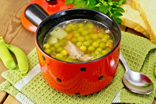 Soup from green peas with meat in red bowl on napkin — Stock Photo, Image