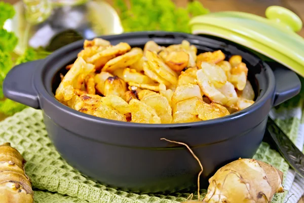 Jerusalem artichokes roasted in pan with lid on board — Stock Photo, Image