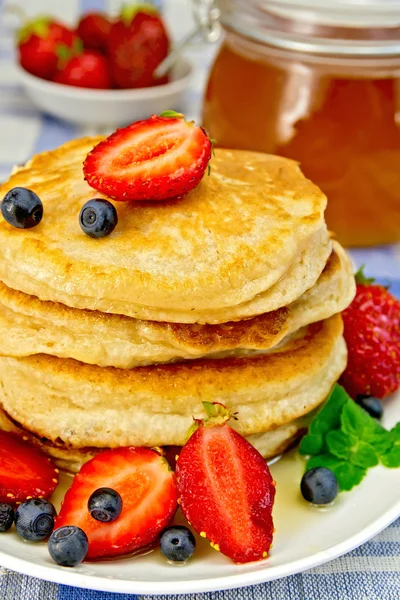 Flapjacks with strawberries and blueberries on linen tablecloth — Stock Photo, Image