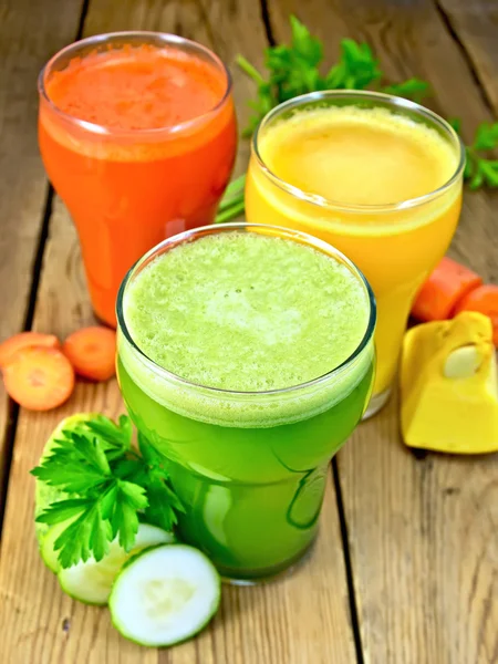 Сок овощной в трех стаканах с овощами на столе — стоковое фото