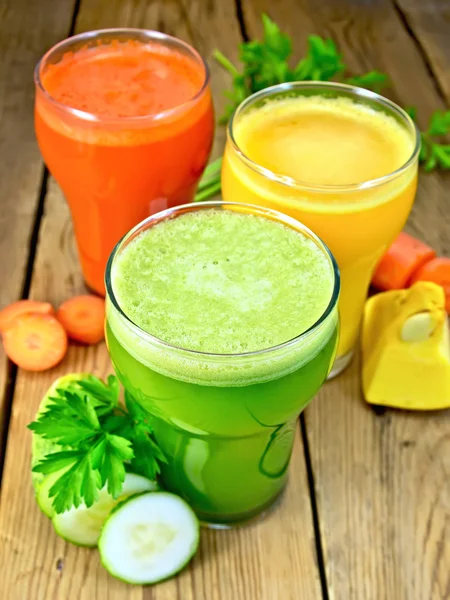 Jus de légumes en trois verres avec des légumes sur la table — Photo