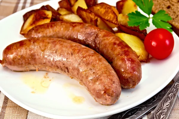 Würstchen Schweinefleisch gebraten mit Kartoffeln und Tomaten auf Teller — Stockfoto