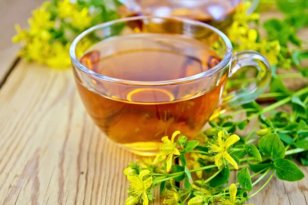 Tea from tutsan in glass cup on board — Stock Photo, Image