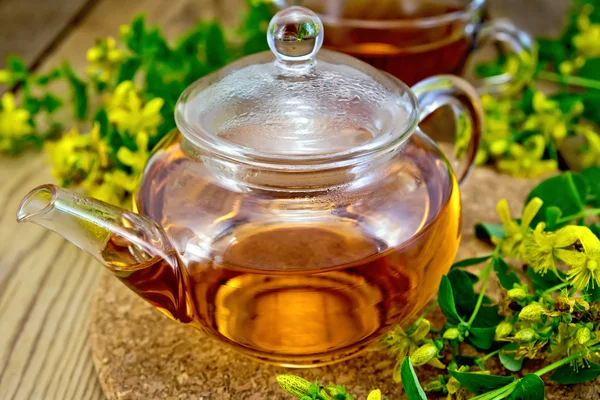 Tea from tutsan in glass teapot on board — Stock Photo, Image