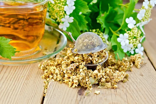 Tee aus Viburnum-Blüten in Glasschale und Sieb an Bord — Stockfoto