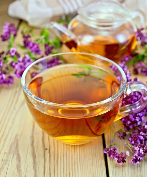 Tea of oregano in glass cup on board with teapot — Stock Photo, Image