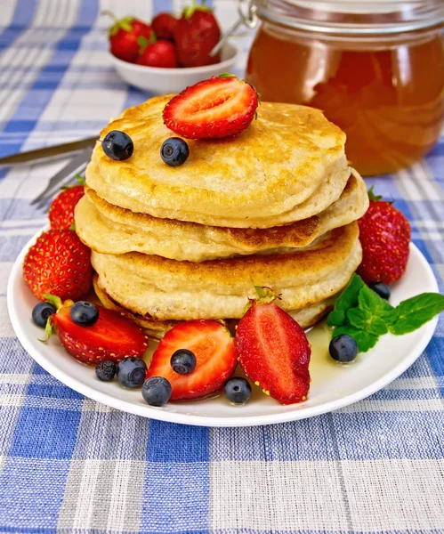 Flapjacks with strawberries and blueberries on blue tablecloth — Stock Photo, Image