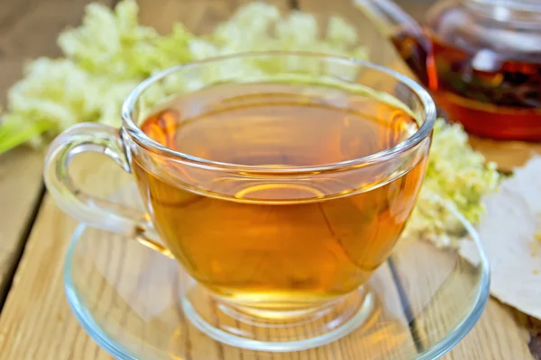 Chá de meadowsweet em copo de vidro e bule a bordo — Fotografia de Stock