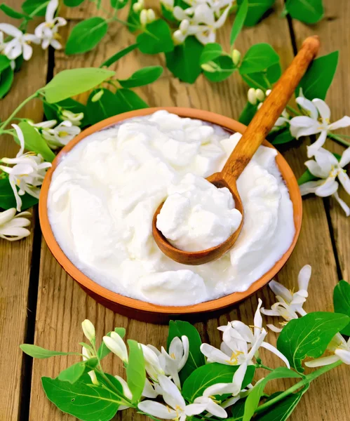 Iogurte em tigela de barro com colher e flores de madressilva — Fotografia de Stock