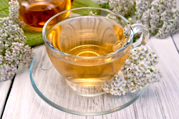 Té con milenrama en taza de vidrio en tablero ligero —  Fotos de Stock