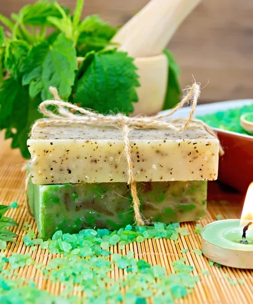 Soap homemade and candle with nettles in mortar on board — Stock Photo, Image