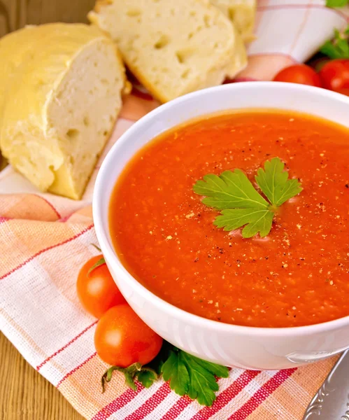 Soupe de tomates dans un bol avec du pain sur la serviette — Photo