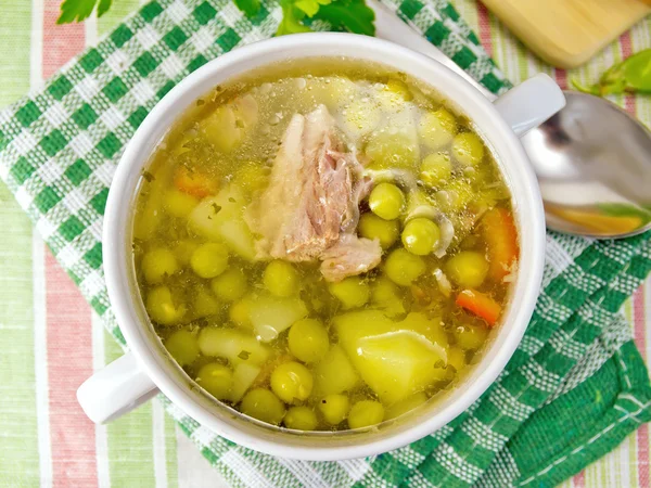 Soup of green peas with meat on tablecloth — Stock Photo, Image