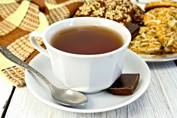 Tee in weißer Tasse mit verschiedenen Keksen auf heller Tafel — Stockfoto