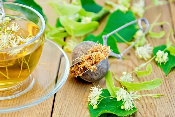 Herbal tea of linden flowers in strainer with cup — Stock Photo, Image