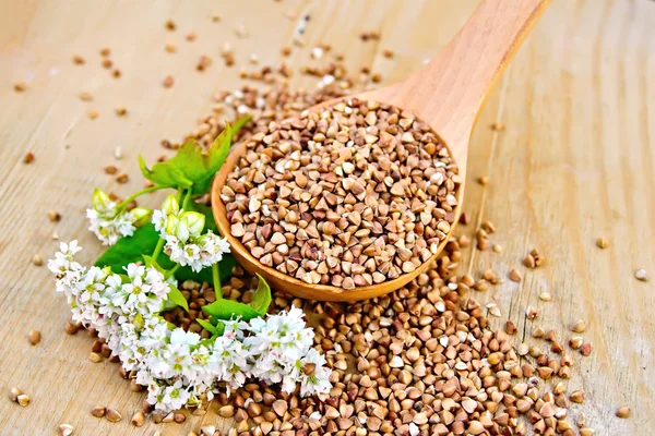 Buckwheat in spoon on board with flower — Stock Photo, Image