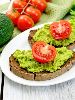 Sandviç guacamole ve ışığı kartı üzerinde domates ile
