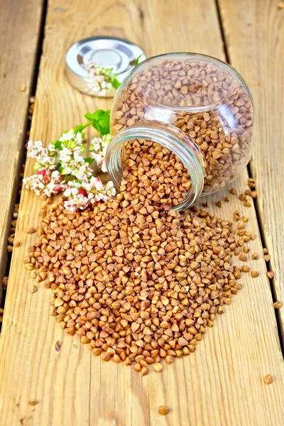 Buckwheat in glass jar and on board with flower — Stock Photo, Image