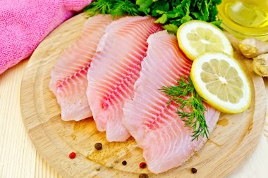 Tilapia with oil and lemon on light board clipart