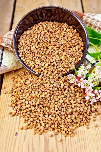 Buckwheat in brown bowl with flower and towel on board — Stock Photo, Image