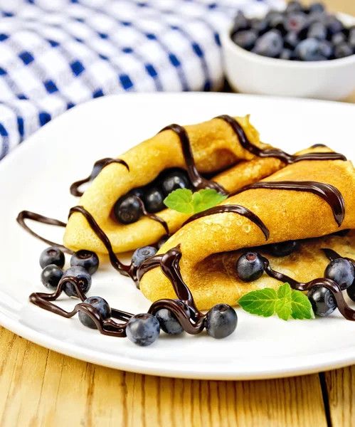 Pancakes with blueberries and chocolate on wooden board — Stock Photo, Image