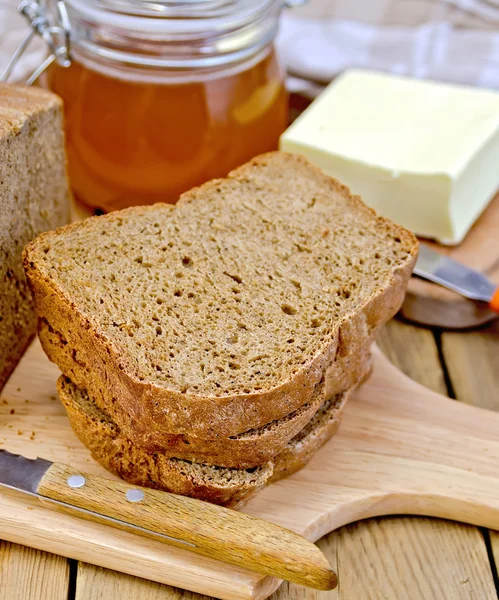 Rye homemade bread with honey and butter on board — Stock Photo, Image