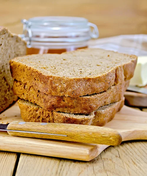 Pane fatto in casa di segale con miele e coltello a bordo — Foto Stock