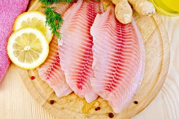 Tilapia with parsley and lemon on light board — Stock Photo, Image