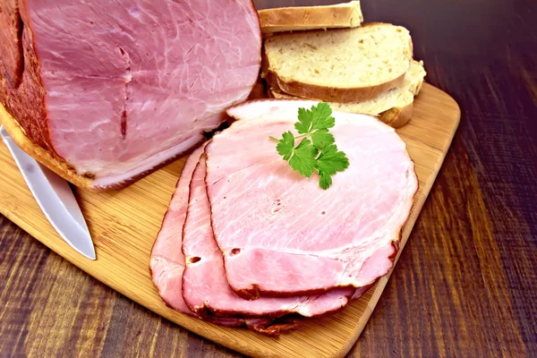 Jambon fumé avec du pain sur une planche sombre — Photo