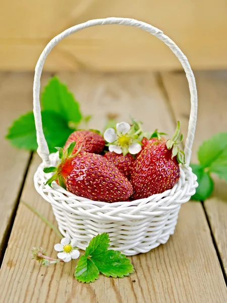 Strawberries in basket with flowers and leaves on board — Stock Photo, Image