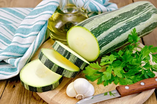 Zucchini green striped with garlic and oil on board — Stock Photo, Image