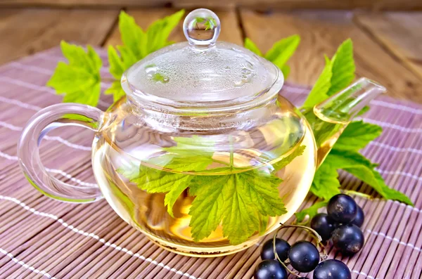 Tee mit schwarzen Johannisbeeren in Glas Teekanne an Bord — Stockfoto