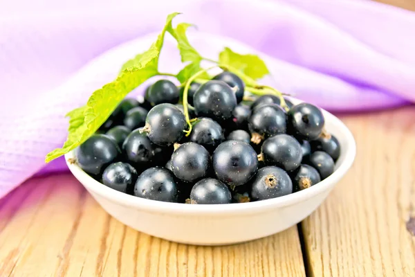 Black currants in bowl with napkin on board — Stock Photo, Image