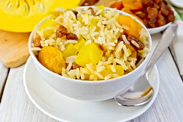 Pilaf fruit with pumpkin in bowl and spoon on board — Stock Photo, Image