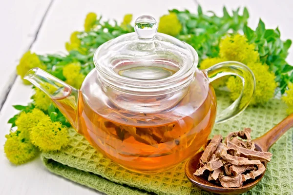 Tea of Rhodiola rosea in glass teapot with spoon on board — Stock Photo, Image