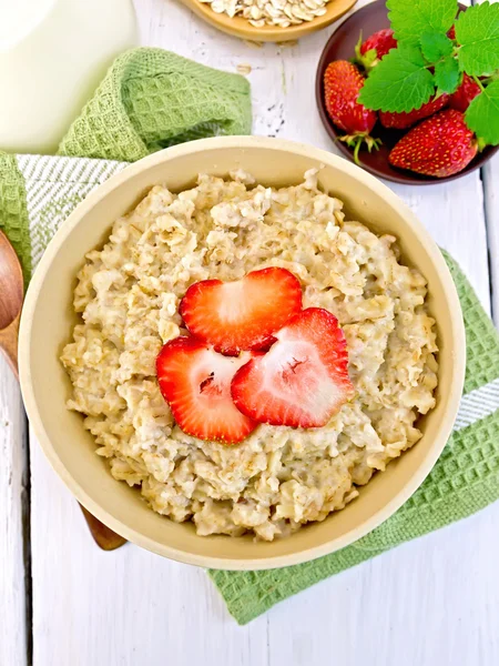 Oatmeal with strawberry on light board top — Stock Photo, Image