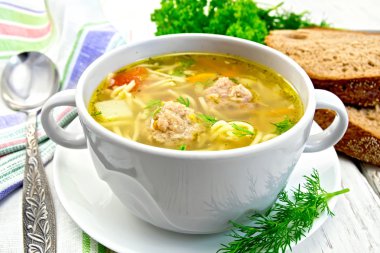 Soup with meatballs and noodles in bowl on saucer