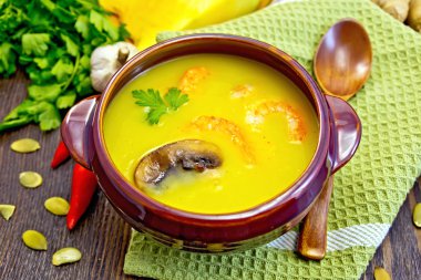 Soup-puree pumpkin with prawns and mushrooms on green napkin