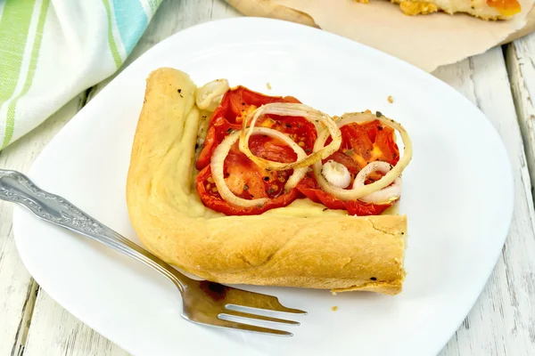 Пиріг з цибулею і помідорами в білій тарілці на дошці — стокове фото