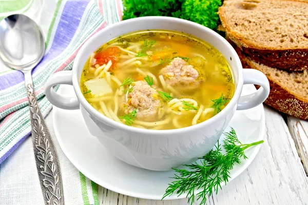 Soup with meatballs and noodles in bowl on board — Stock Photo, Image