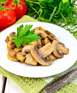 Champignons fried in plate with fork on light board